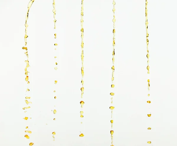 柠檬汁或润滑油飞溅 金黄色液体饮料滴落 水果饮料中的水元素呈直线状 新鲜的飞溅和流动的射流 白色背景隔离冻结运动 — 图库照片