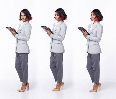 20 'li yaşlarda Asyalı bir kadın resmi iş elbisesi, yüksek topuklu ayakkabı giyer. Siyah kısa kıvırcık saçlı kadın mutlu bir gülümseme hisset tableti tut, arka taraf 360, arka taraf beyaz arka plan izole