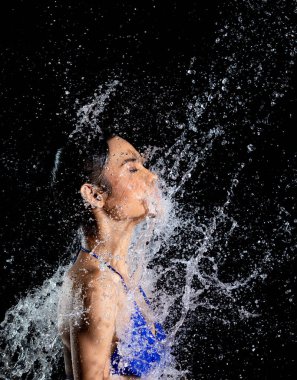 Bikini giymiş bronz tenli Asyalı kadın Aqua stüdyosunda poz veriyor. Vücuda yayılmış su damlaları. Eğlenceli duygu. Suya atlayan kadın. Titreyen ve durduran hareketsiz çekim.
