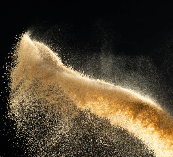 Sand flying explosion, Golden sand wave explode. Abstract sands cloud fly. Yellow colored sand splash throwing in Air. Black background Isolated selective focus, throwing motion Blur