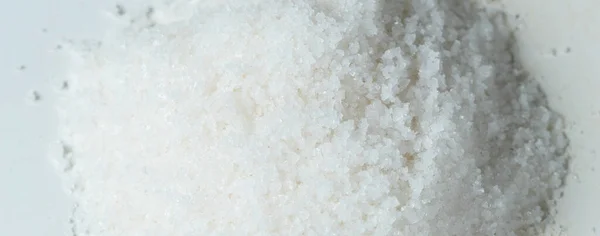 成堆的盐 晶莹的白粒盐倾泻下来 形成了抽象的云团 美丽完整的种子盐 食物物体的设计 选择性聚焦冻结拍摄白色背景隔离 — 图库照片