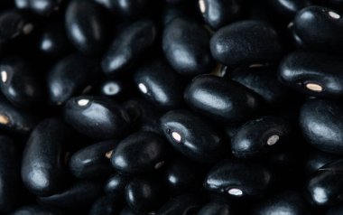 Makro, siyah fasulye dokusu, yuvarlak fasulye. Güzel bir bezelye tohumu, yiyecek nesnesi tasarımı. Seçici odak dondurucu çekim siyah arkaplan izole