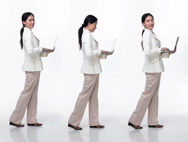 全长20多岁的亚洲女人穿着正式的商务西装 连衣裙 平底鞋 黑色长发女性抱着笔记本电脑工作自信 向前走向左拐 白色背景隔离 — 图库照片
