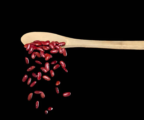 Red Bean fall, red grain beans explode abstract cloud fly from wooden spoon. Beautiful complete seed pea bean, food object design. Selective focus freeze shot black background isolated