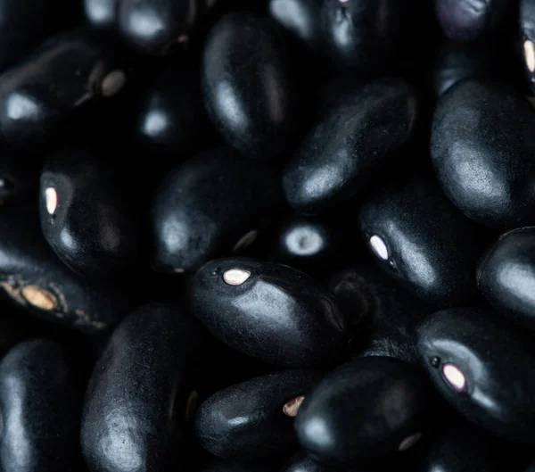 Makro, siyah fasulye dokusu, yuvarlak fasulye. Güzel bir bezelye tohumu, yiyecek nesnesi tasarımı. Seçici odak dondurucu çekim siyah arkaplan izole
