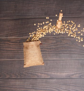 Soy Bean flying explosion in sack bag, yellow grain beans explode abstract cloud fly. Beautiful complete seed pea soy bean sack bag splash in air, food object design. Wooden background isolated freeze