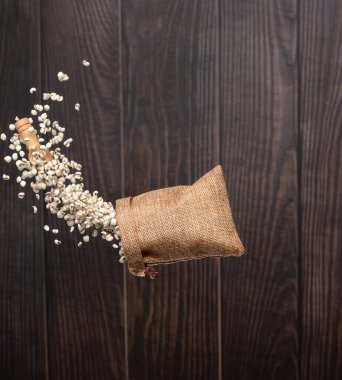 Job's Tear flying in sack bag, white grain job tear float abstract cloud fly. Beautiful job's tear sack bag splash in air, food object design. Wooden background isolated high speed freeze motion