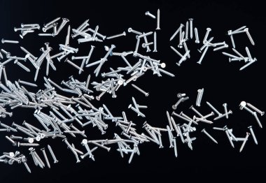 Tornavida sineği havada süzülüyor. Birçok grup çivi çakar. İnşaat aracı olarak uzun metaller düşer. Siyah arka plan izole. Yeni tornavida çivisi kutusuz çelik donanım işçiliğinden düştü