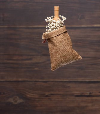 Job's Tear flying in sack bag, white grain job tear float abstract cloud fly. Beautiful job's tear sack bag splash in air, food object design. Wooden background isolated high speed freeze motion