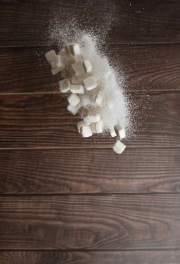 Sugar Cube in sack bag flying explosion, white crystal sugar fall abstract fly. Pure refined sugar cubes bag splash in air, food object design. wood kitchen background, high speed freeze motion
