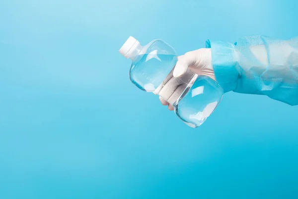 Saline medical cleaning normal solution plastic bottle in hand of nurse with glove, clear of normal saline in plastic bottle to clean nose sterile medical equipment over blue background isolated