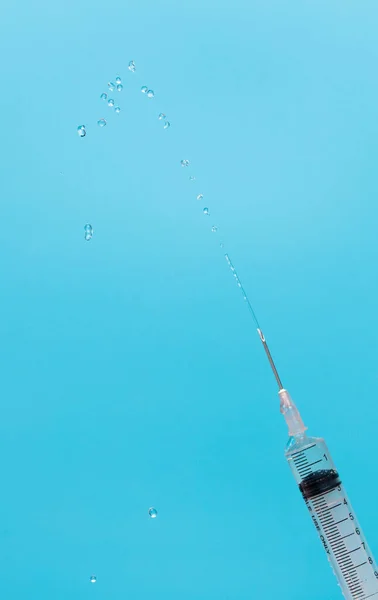 Syringe inject serum cure drug from needle tube and fly in air. Syringe push up testing and get rid of oxygen air in tube out. Syringe with sharp needle in hand. Medical over blue background isolated