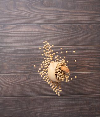 Soy Bean flying explosion in wood bowl, yellow grain beans explode abstract cloud fly. Beautiful complete seed pea soy bean bowl splash in air, food object design. Wooden background isolated freeze