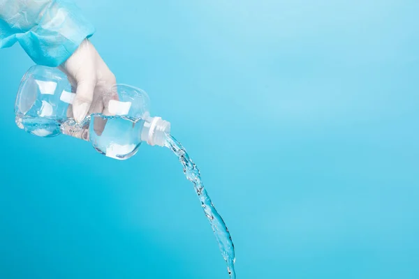 盐水医疗清洗护士手拿普通溶液塑料瓶用手套 将普通盐水倒入塑料瓶中 在蓝色背景隔离的情况下清洗消毒医疗设备 — 图库照片