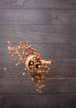 Ahşap kasede uçan yer fıstığı, soyut şamandıralar fırlatıyor. Fıstık ezmesi kasesi havaya sıçrıyor. Gıda nesnesi tasarımı. Ahşap arka plan yüksek hız deklanşör dondurucu çekim