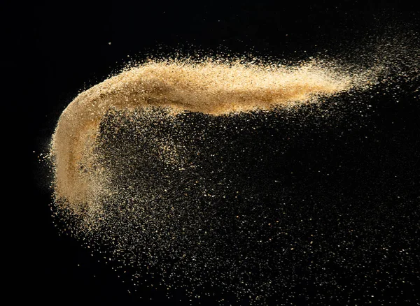 Sand flying explosion, Golden sand wave explode. Abstract sands cloud fly. Yellow colored sand splash throwing in Air. Black background Isolated high speed shutter, throwing freeze stop motion