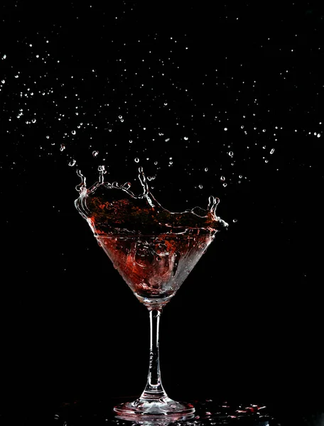 Red Cocktail Glass with splashing water alcohol, Crystal Cocktail drink splatter splash in air and bubble from glass. Liquor Part freeze shot high speed over black background isolated