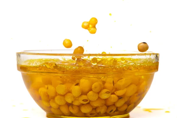 野菜油中の黄色い大豆は空気中に落ちます 黄金の大豆はボウルに注ぐ調理油と混合し 大豆は健康的な食事や食品成分調理成分です 隔離された白い背景 — ストック写真