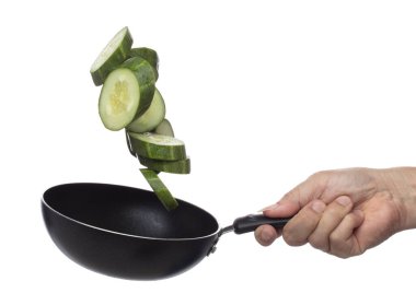 Cucumber fly fall in pan, green fresh vegetable cucumber cut chop slice. Organic fresh vegetable with eaten leaf of long cucumber, close up texture. White background isolated freeze motion high speed