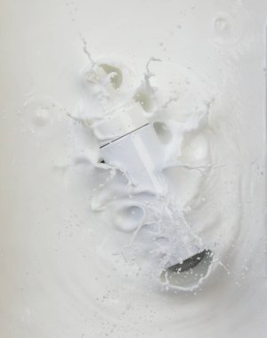 Kozmetik kabı beyaz losyon damlası su sıçratıyor. Süt losyonu kozmetik şişesine dökülür. Nemlendirici losyon sızıntısı. Beyaz arkaplan izole edilmiş yüksek hız deklanşörü üst görünümü dondur