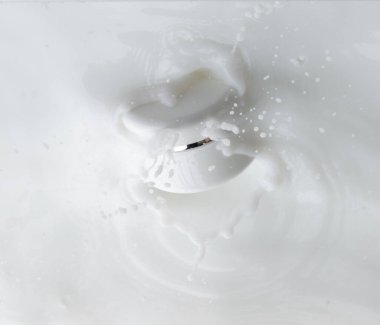 Kozmetik kabı beyaz losyon damlası su sıçratıyor. Süt losyonu kozmetik şişesine dökülür. Nemlendirici losyon sızıntısı. Beyaz arkaplan izole edilmiş yüksek hız deklanşörü üst görünümü dondur