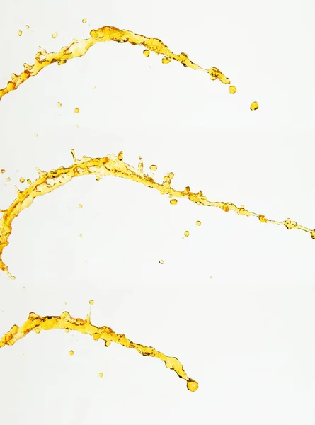 柠檬汁或润滑油飞溅 金黄色液体饮料滴落 水果饮料中的水元素呈直线状 新鲜的飞溅和流动的射流 白色背景隔离冻结运动 — 图库照片