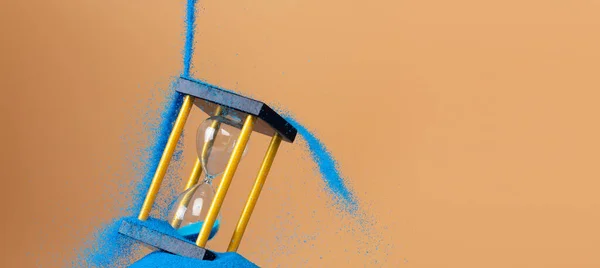 沙漏是金钱的时间沙漏 企业将蓝色沙漏倒入沙漏中 增加了更多的财务时间 截止日期将时间管理的理念延伸到黄金小时玻璃 橙色背景日落 — 图库照片