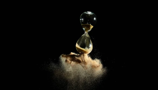 砂時計の空中で飛行 黒の背景に金砂の上に時間のより多くの砂を追加します ブラウン砂時計は より多くの時間を示しています期限延長時間管理希望コンセプト時間ガラス ライフクロックが通過 — ストック写真