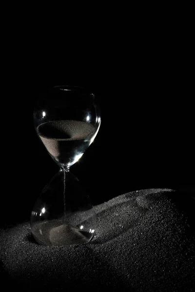 黒の背景の上にシルエットの影と黒砂の上に砂時計スタンド ブラック砂時計は より多くの時間を示しています期限延長時間管理希望コンセプト時間ガラス ライフクロックが通過 — ストック写真