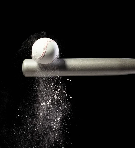 野球選手は銀のバットと砂の土が空中に爆発するボールを打った ダイナミックアクションの野球選手がボールの煙の尾に当たった 黒い背景によって隔離される凍結の行為 — ストック写真