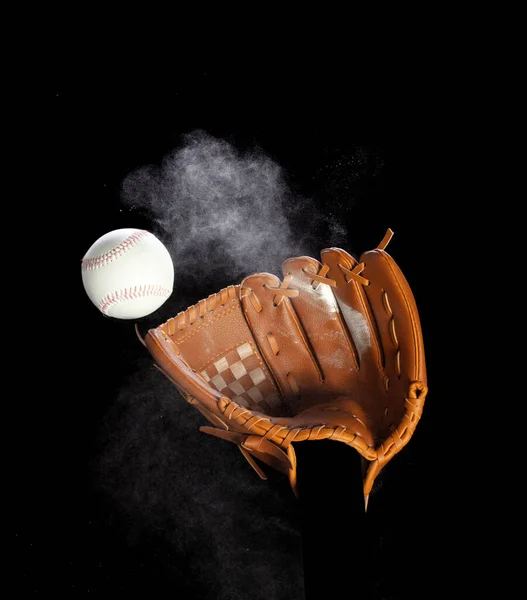 レザーグローブミットは ヒットした野球ボールと塵土が空中で爆発します 野球ボール投げ ミトグローブの中心にヒット 黒い背景によって隔離される凍結の行為 — ストック写真