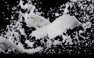 Tuz tozu kaseye dökülür, beyaz tuz kristal aşçı soyut bulut sineği. Yer tuzu havaya sıçrar, yiyecek nesnesi tasarımı. Siyah arkaplan seçici odak bulanıklığı