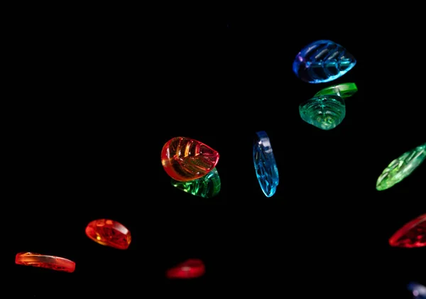 Fashion colorful plastic leaf with beautiful work detail is value. Luxury leaf bead red blue green is fashion trend and fly in air. Black background isolated selective focus blur