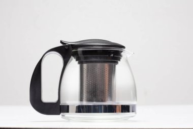 Gevşemek için kuru yaprak çaydanlığına sıcak su koymak için yaprak filtresi ve saplı cam çaydanlık. Kurumuş yaprak çayını filtrelemek için bir çaydanlık. Beyaz arkaplan izole edilmiş fırlatma dondurma hareketi