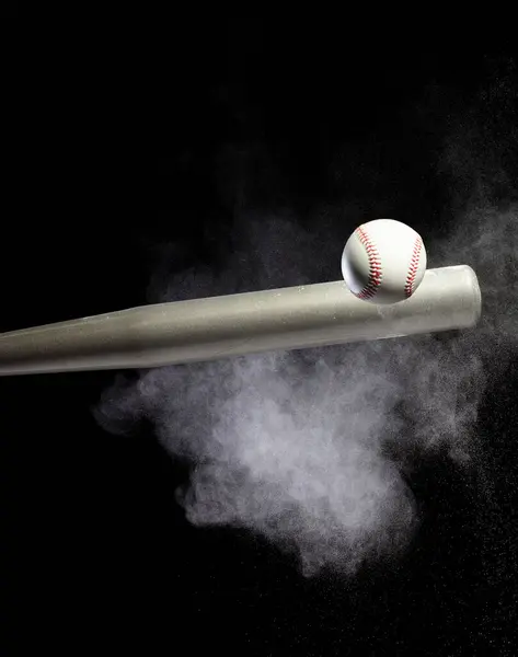 stock image Baseball player hit ball with silver bat and sand soil explode in air. Baseball players in dynamic action hit ball smoke tail. Black background isolated freeze action