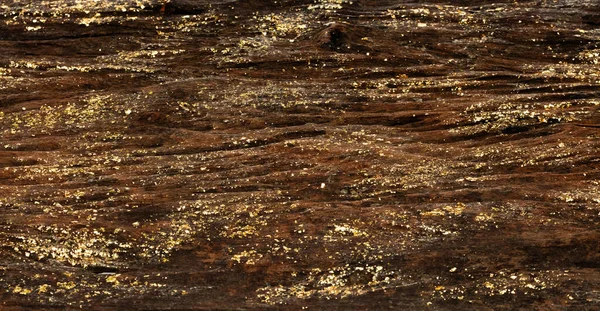 Old wood with gold ore mineral material in fossil wood stone. Gold leaf decorate on wooden background as wallpaper.