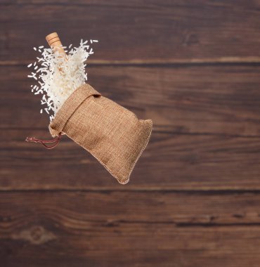 Japanese Rice in sack bag flying explosion, white grain rices fall abstract fly. Beautiful complete seed rice bag splash in air, food object design. Wood kitchen background, high speed freeze motion