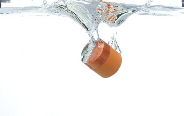 橙色的化妆品容器与气泡一起落入清澈的水中 化妆品处理容器滴入清澈的淡水中 白色背景隔离冻结元件 — 图库照片