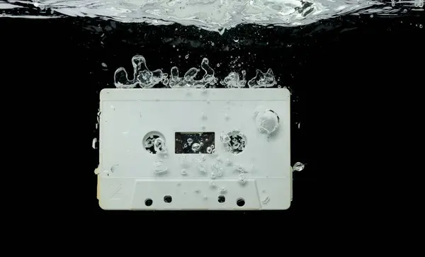 盒式磁带复古时带着气泡掉进清澈的水中 黑色复古复古盒式磁带掉到清洗旧时间 黑色背景隔离冻结元件 — 图库照片