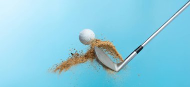 Kum sığınağından golf topu tişörtü patladı. Golf sopası ile topa vuran golfçü, yaz gökyüzünde kum patlamasına yol açtı. Golf sopası, kum deposu patlamasında topa vurdu. Mavi arkaplan izole edilmiş dondurucu hareket