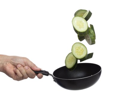 Cucumber fly fall in pan, green fresh vegetable cucumber cut chop slice. Organic fresh vegetable with eaten leaf of long cucumber, close up texture. White background isolated freeze motion high speed