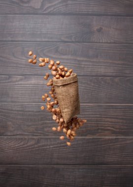 Peanut flying in sack bag, brown grain peanuts throw abstract float. Beautiful complete seed pea peanut sack bag splash in air, food object design. Wooden background high speed shutter freeze shot