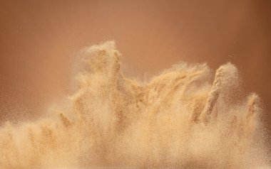 Small Fine size Sand flying explosion, Golden grain wave explode, abstract cloud fly. Yellow colored sand splash throwing in Air. Aura wallpaper background high speed shutter, freeze stop motion