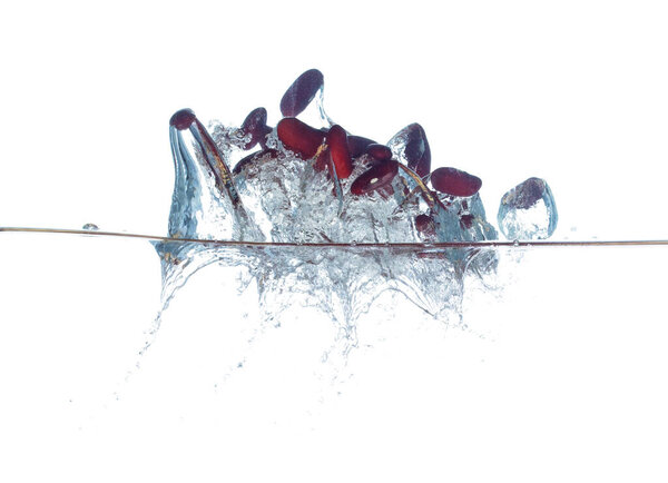 Red liver Beans falls into water and creates air bubbles on surface. Red beans drop hit smash to boil water and deep to bubble. White background isolated freeze motion