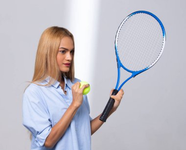 Engelli kadın sarışın saçlar raket ve tenis topunu spor olsun diye tutuyor. Solaryum tenli, parmakları sakat bir kadın tenis topu ve raket tutabilir. Beyaz arkaplan izole