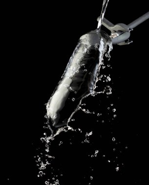 Pantolonun üzerine su dökmek şekil vermek için bir nesne. Damlacıklar ve dalgalar halinde çırpınıyor. Nesnelere su dökmek eğrinin yön değiştirmesine neden olur. Siyah arkaplan izole