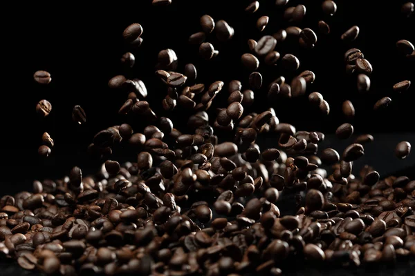 Coffee roasted bean fly explosion, Coffee crushed float pouring mix with beans. Roasted Coffee bean splash explosion in mid Air. Black background Isolated selective focus blur