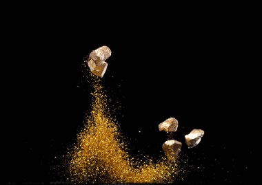 Altın külçeli Çin Para Çubuğu. Toz parçacığı havada uçuşuyor. Çin 'in yeni yılı Yuanbao altınları altın para ve kum tanecikleri arasında yüzüyor. Dil zengin bir refahtır. Siyah arkaplan izole