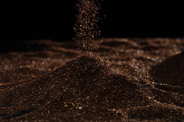 Ground Coffee roasted powder dust fly explosion, Coffee crushed ground float pouring. Roasted Coffee powder ground dust splash explosion in mid Air. Black background Isolated selective focus blur