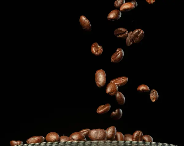 Roasted Coffee seeds with smoke. Beans Coffee roasted on pile and hot smoke raise up in line shape. Roasted coffee bean create scent aroma. Black background isolated